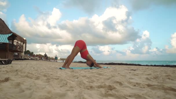 Pembe takım elbiseli kadın deniz kenarında yoga yapıyor. Mavi halı Telifsiz Stok Video