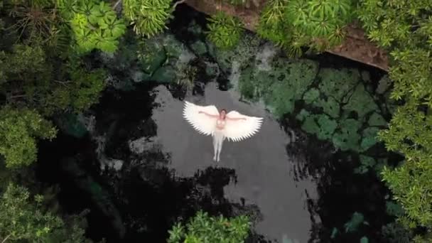 Vista superior de la mujer flotando en las alas del ángel en el lago del cenote en México — Vídeos de Stock