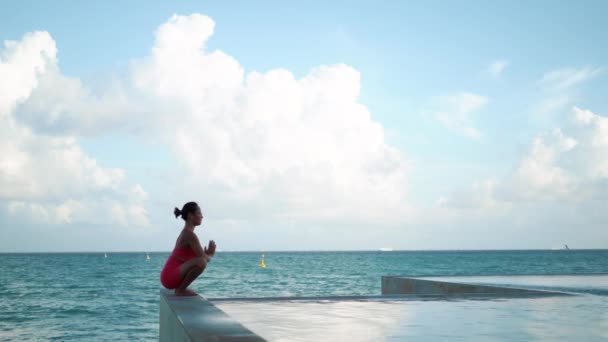 Młoda atrakcyjna kobieta w pozycji jogi w pobliżu basenu na zachodzie słońca szeroki strzał — Wideo stockowe