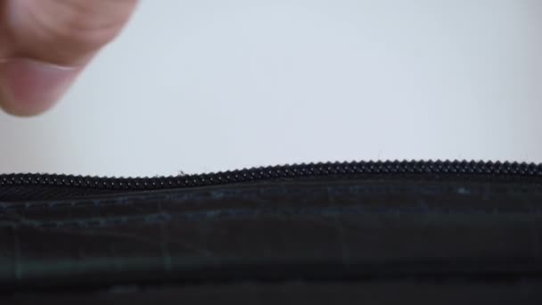 Close-up of a man closing zipper on black small bag. blurred background — Stock Video