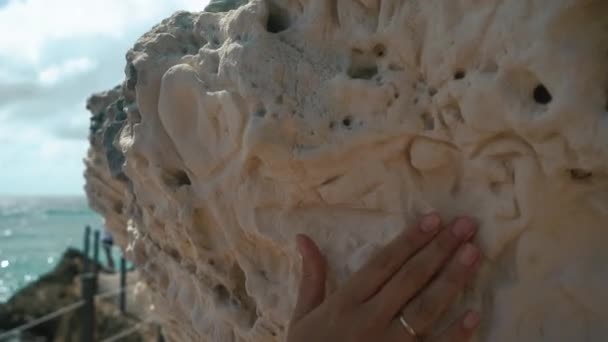 Close-up dari tangan perempuan menyentuh ke langkan berbatu. Sandy cliff — Stok Video