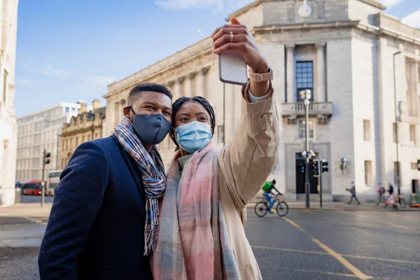 Casal Cidade Usando Máscaras Faciais Segurando Telefone Celular Tomando Selfie — Fotografia de Stock