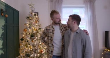 Bir LGBTQI 'nin ön görüntüsü. Oturma odalarında duran aynı cinsiyetten erkek çift, Noel hediyelerini değiş tokuş ediyorlar..