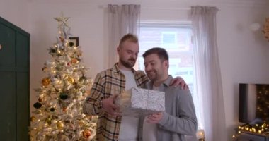 Bir LGBTQI 'nin ön görüntüsü. Oturma odalarında duran aynı cinsiyetten erkek çift, Noel hediyelerini değiş tokuş ediyorlar..