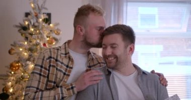 Bir LGBTQI 'nin ön görüntüsü. Oturma odalarında duran aynı cinsiyetten erkek çift, Noel hediyelerini değiş tokuş ediyorlar..