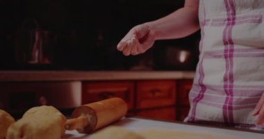 Kadın Sifts kruvasan pişirirken mutfakta süzgeçten un geçiriyor..