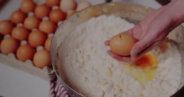 Female hand breaks fresh chicken egg into bowl.