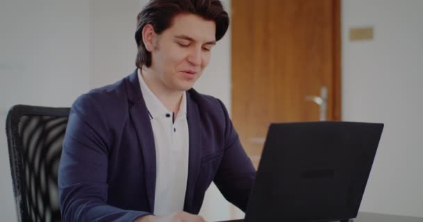 Позитивный человек в офисе работает над ноутбуком — стоковое видео