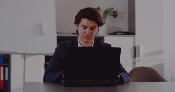 若いビジネスマンは自宅のオフィスからラップトップで働いています. — ストック動画