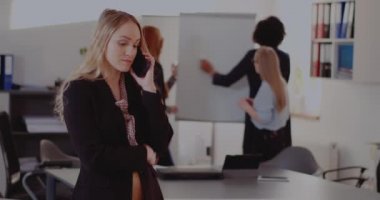 İş kadını ofiste cep telefonuyla konuşuyor.