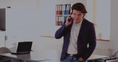 İşadamı ofiste akıllı telefondan konuşuyor.