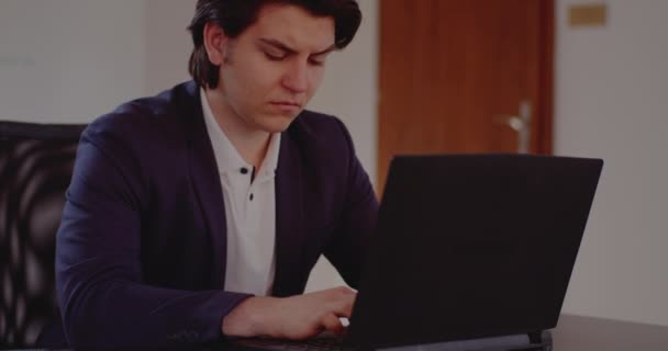 Jovem empresário tenso usando laptop no escritório — Vídeo de Stock