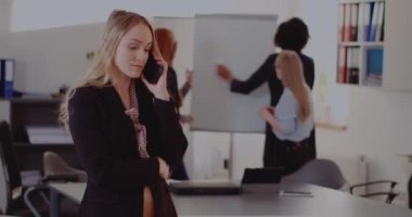 İş kadını ofiste cep telefonuyla konuşuyor.