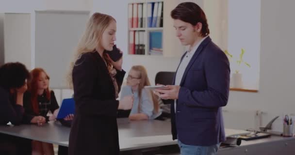 Бизнесмен показывает планшетный компьютер коллеге, разговаривающему по телефону — стоковое видео