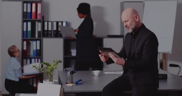 Зрелый бизнесмен с помощью планшетного ПК на столе в офисе — стоковое видео