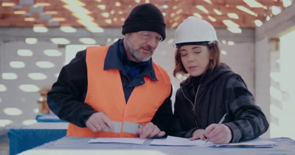 Ingénieurs concentrés discutant, examinant et développant sur le chantier — Video