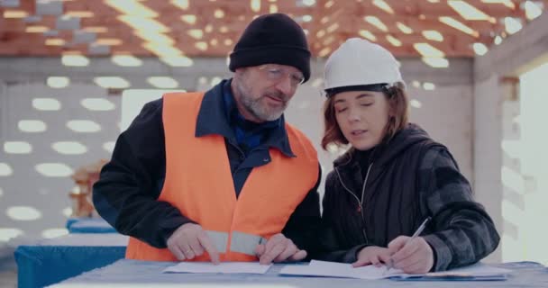 Konzentrierte Ingenieure diskutieren, untersuchen und entwickeln auf der Baustelle — Stockvideo