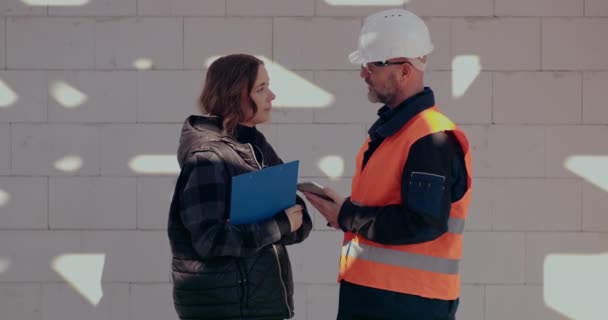 Ingenieros concentrados discutiendo, examinando y desarrollando en el sitio de construcción — Vídeo de stock