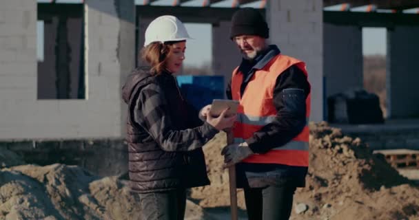 Konzentrierte Ingenieure diskutieren, untersuchen und entwickeln auf der Baustelle — Stockvideo