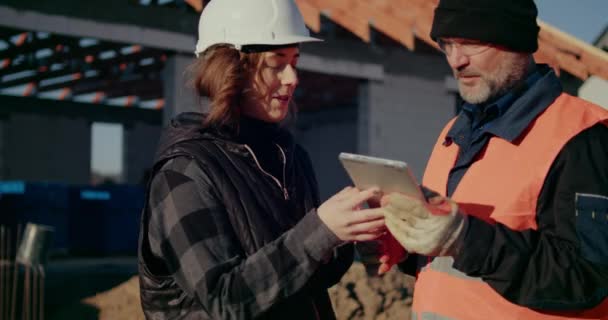 Koncentrerade ingenjörer diskuterar, undersöker och utvecklar på byggarbetsplatsen — Stockvideo