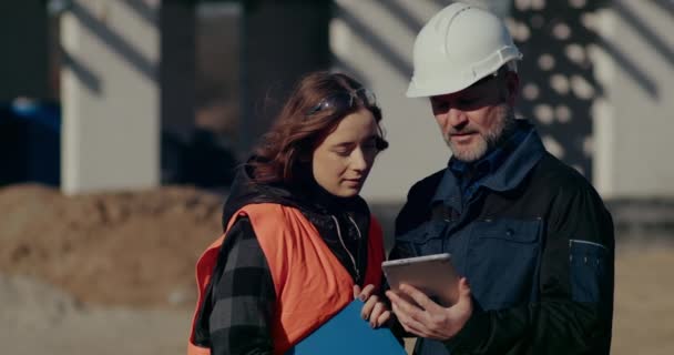 Konzentrierte Ingenieure diskutieren, untersuchen und entwickeln auf der Baustelle — Stockvideo