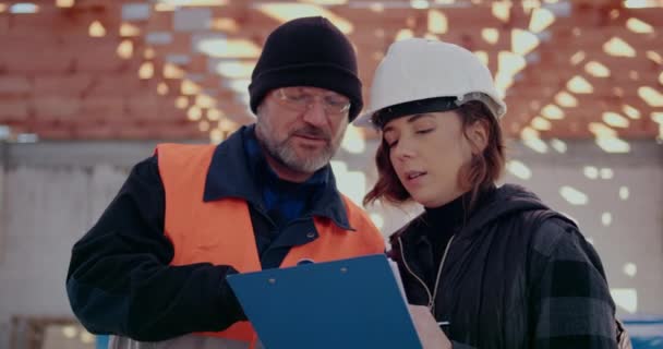 Ingénieurs concentrés discutant, examinant et développant sur le chantier — Video