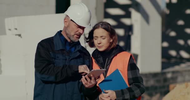 Ingenieros concentrados discutiendo, examinando y desarrollando en el sitio de construcción — Vídeo de stock