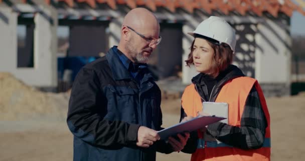 Koncentrerade ingenjörer diskuterar, undersöker och utvecklar på byggarbetsplatsen — Stockvideo