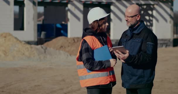 Концентрированные инженеры обсуждают, изучают и развивают на строительной площадке — стоковое видео