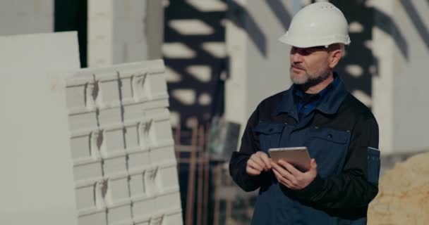 Строитель с помощью цифрового планшета на строительной площадке — стоковое видео
