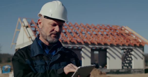 Trabalhador de Costrução usando tablet digital no canteiro de obras — Vídeo de Stock