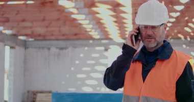 İnşaat alanında Costruction Worker cep telefonundan konuşuyor.