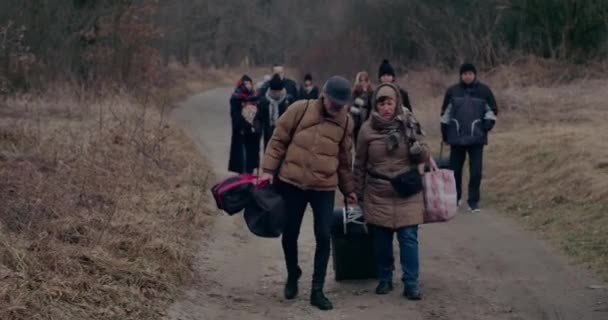 Muž pomáhá uprchlík žena bojuje s táhnoucí zavazadla. — Stock video