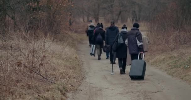 Krigsflyktingar med bagage promenader på vägen under snöfall. — Stockvideo