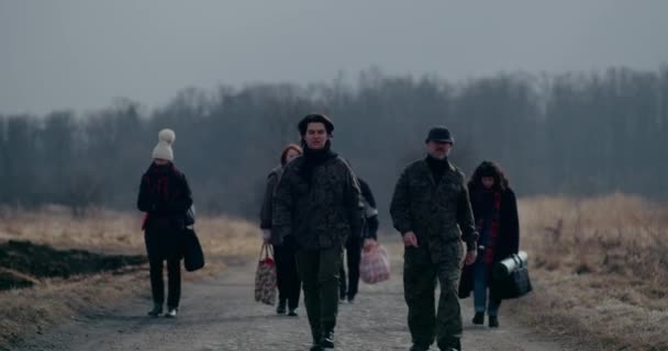 Katonai katonák sétálnak a Menekültcsoport előtt az úton. — Stock videók