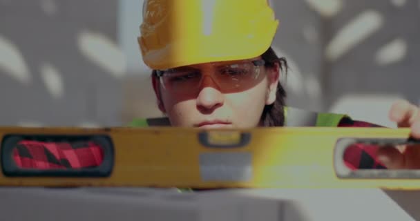 Männlicher Bauarbeiter begutachtet Mauer mit Niveau — Stockvideo