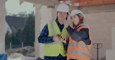 İş arkadaşları inşaat alanında akıllı telefondan tartışıyorlar.