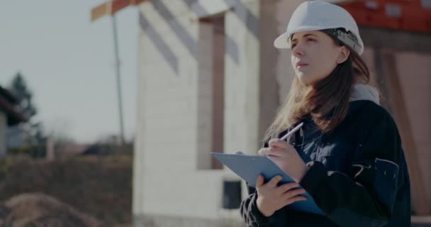 Fiatal női építész írás vágólapra a helyszínen — Stock videók