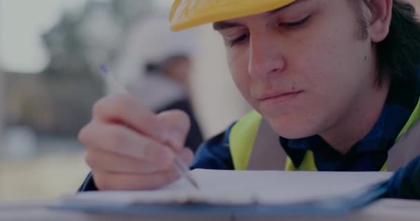 Confident male building contractor drawing while analyzing blueprint — Video