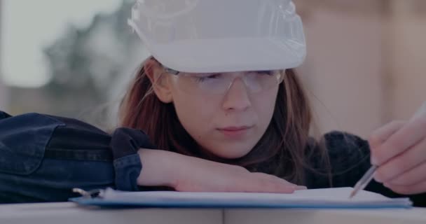 Magabiztos fiatal női építész tervrajzot készít a helyszínen — Stock videók