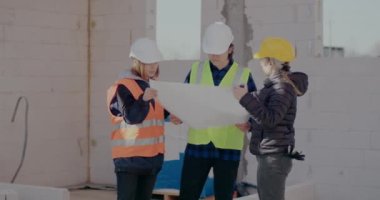 İşçilerle planı analiz eden ve tartışan mühendis.