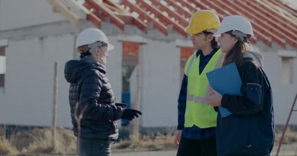 Női építőmérnök üdvözlő építőipari vállalkozó és munkavállaló kézfogással — Stock videók