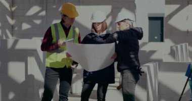 Mühendis ve mimar, müteahhitlerin planları üzerinde tartışıyorlar.