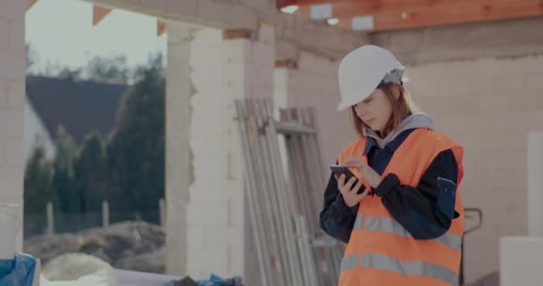 Молода жінка будівельник використовує смартфон — стокове відео