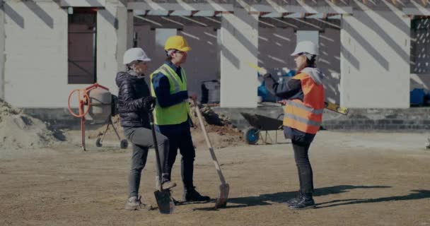 Byggnadsentreprenör diskuterar med byggmedarbetare — Stockvideo