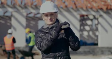 Kendine güvenen kadın mühendis omzunda bir araç taşıyor.