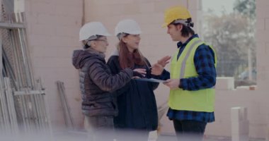 Kadın mühendis ve yönetici, erkek iş arkadaşıyla pano üzerinde tartışıyor.