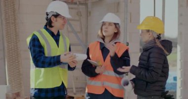 Mühendisle inşaat planı üzerinde tartışan iş arkadaşları