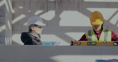 Kadın müteahhit ve işçi duvarı düzeyi ile inceliyor.