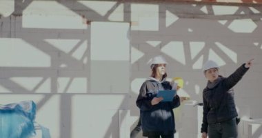 Kadın mimar mühendise açıklarken el kol hareketi yapıyor.